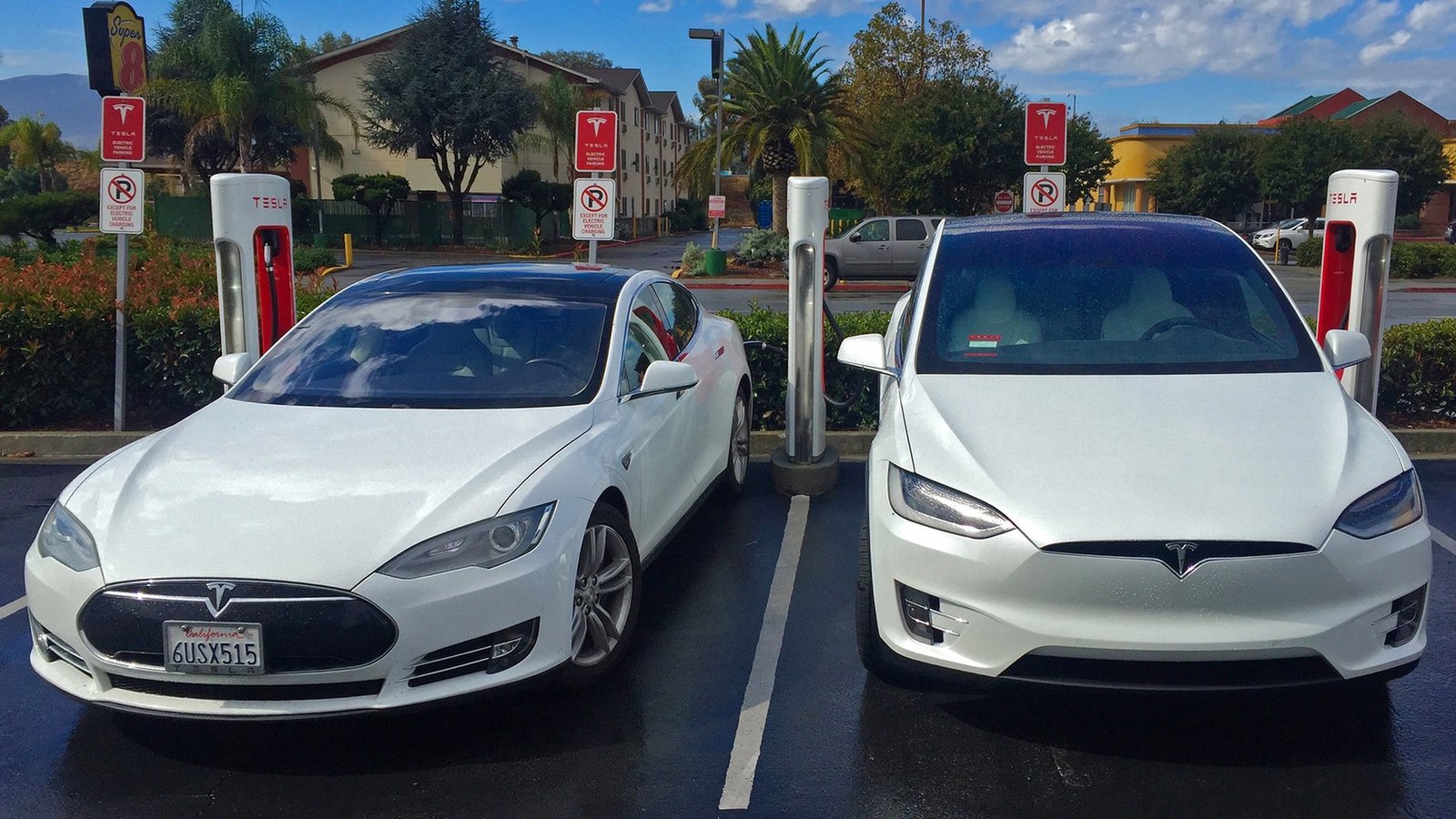 Two electric cars charging side by side at a public rapid charging station