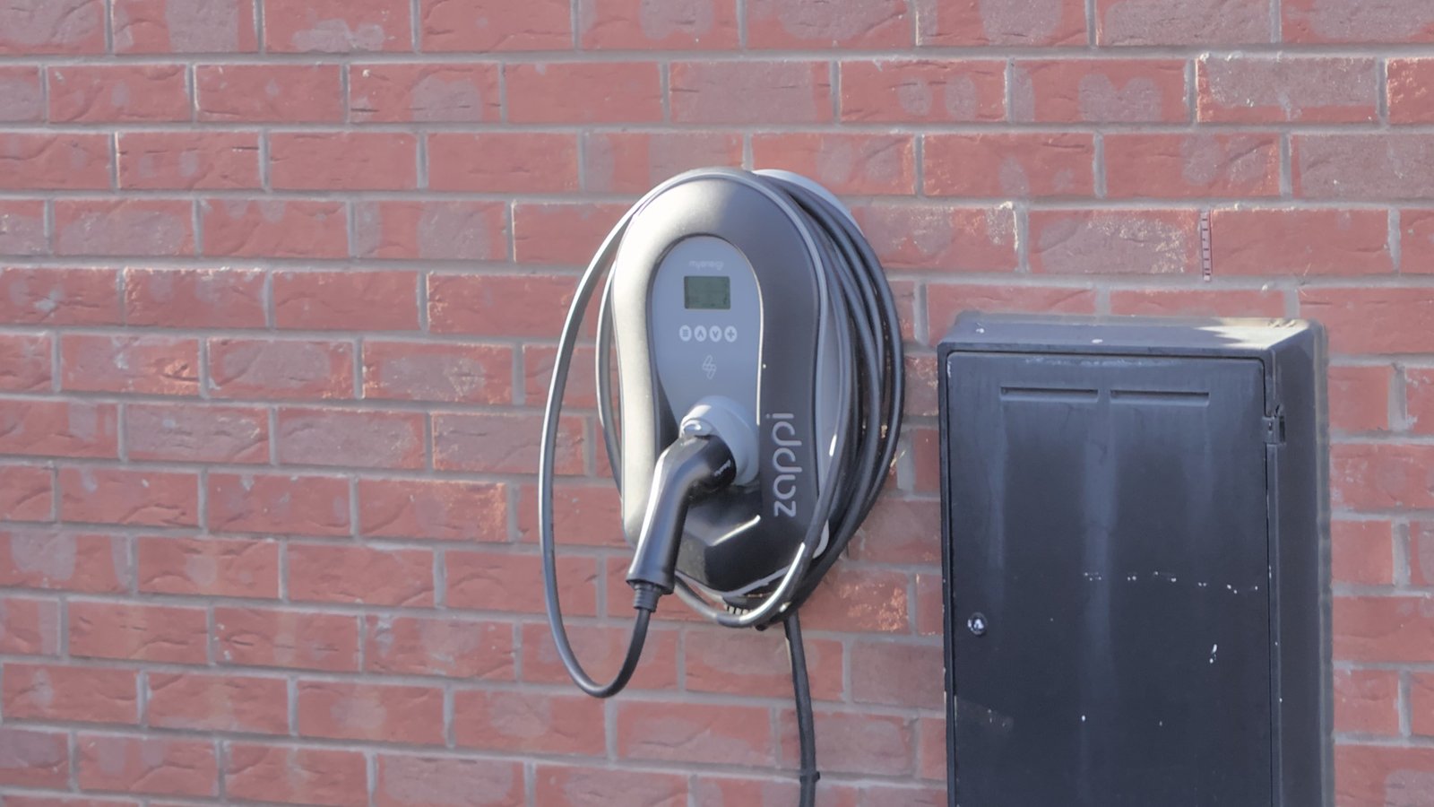 myenergi Zappi home EV wallbox mounted on a brick wall with cable coiled